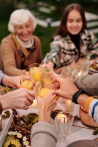 Faceless group of people enjoying family reunion and toasting with orange juice spending time in garden
